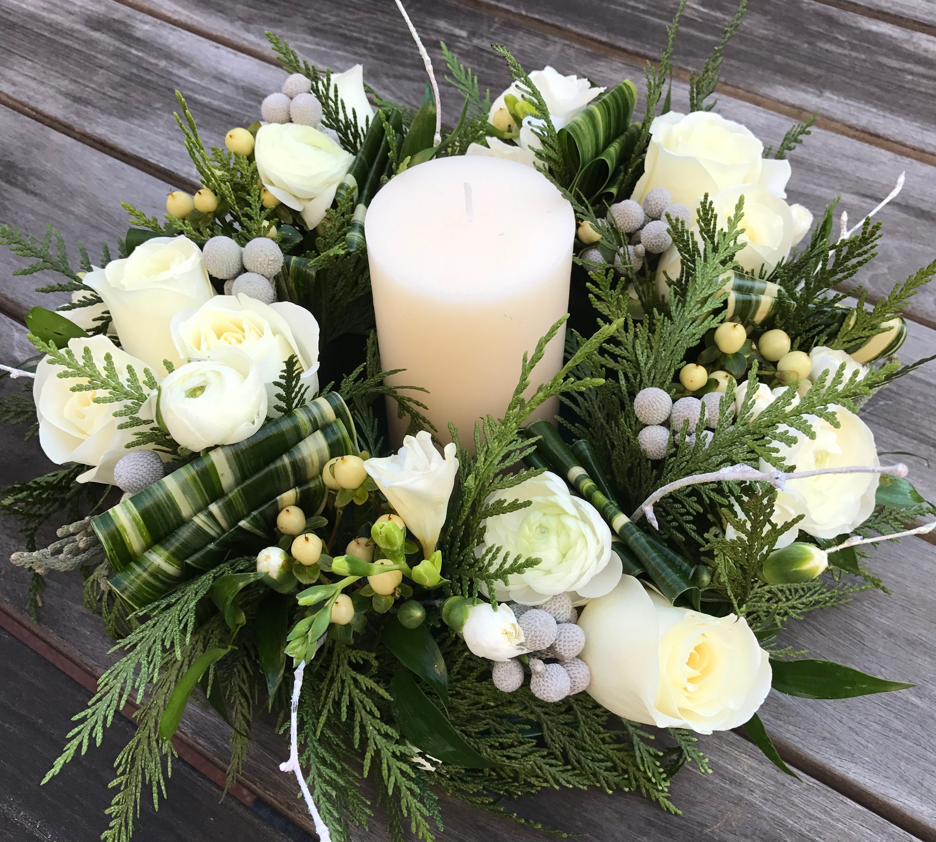 A green mini wreath with white flowers has a candle in the middle