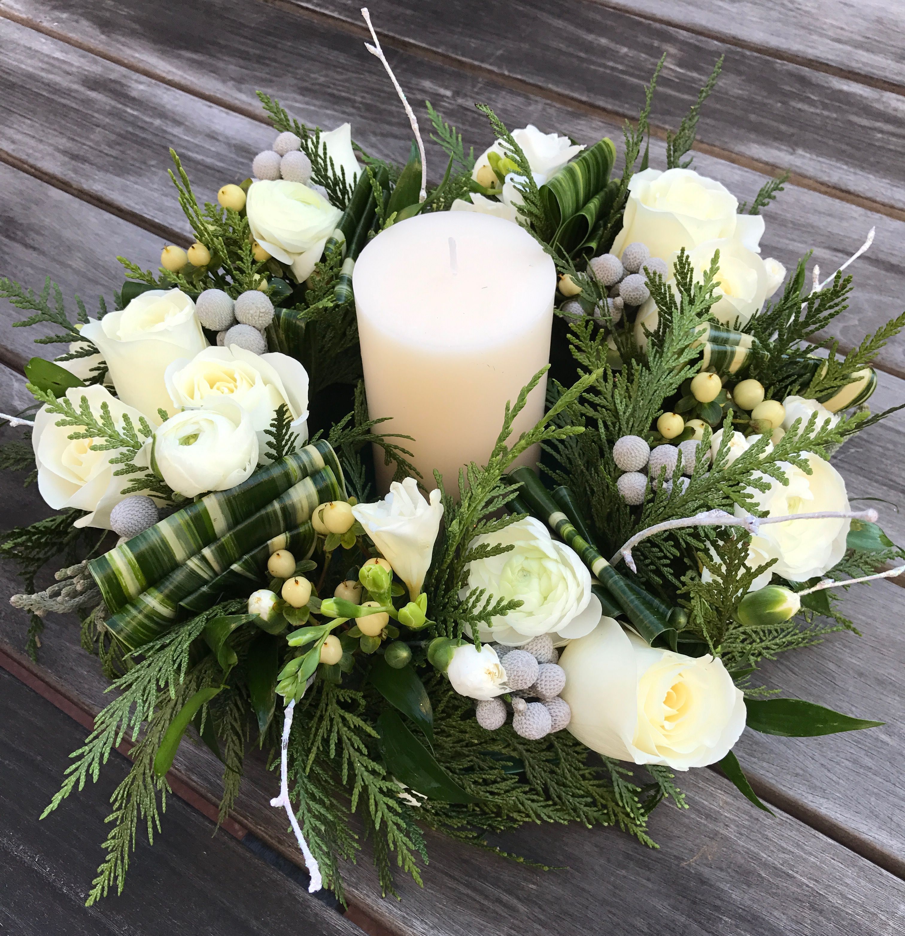 A green mini wreath with white flowers has a candle in the middle